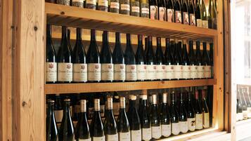 A wooden wine rack with multiple shelves holding wine bottles.