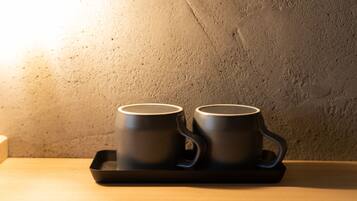 Two black mugs on a tray against a textured wall.