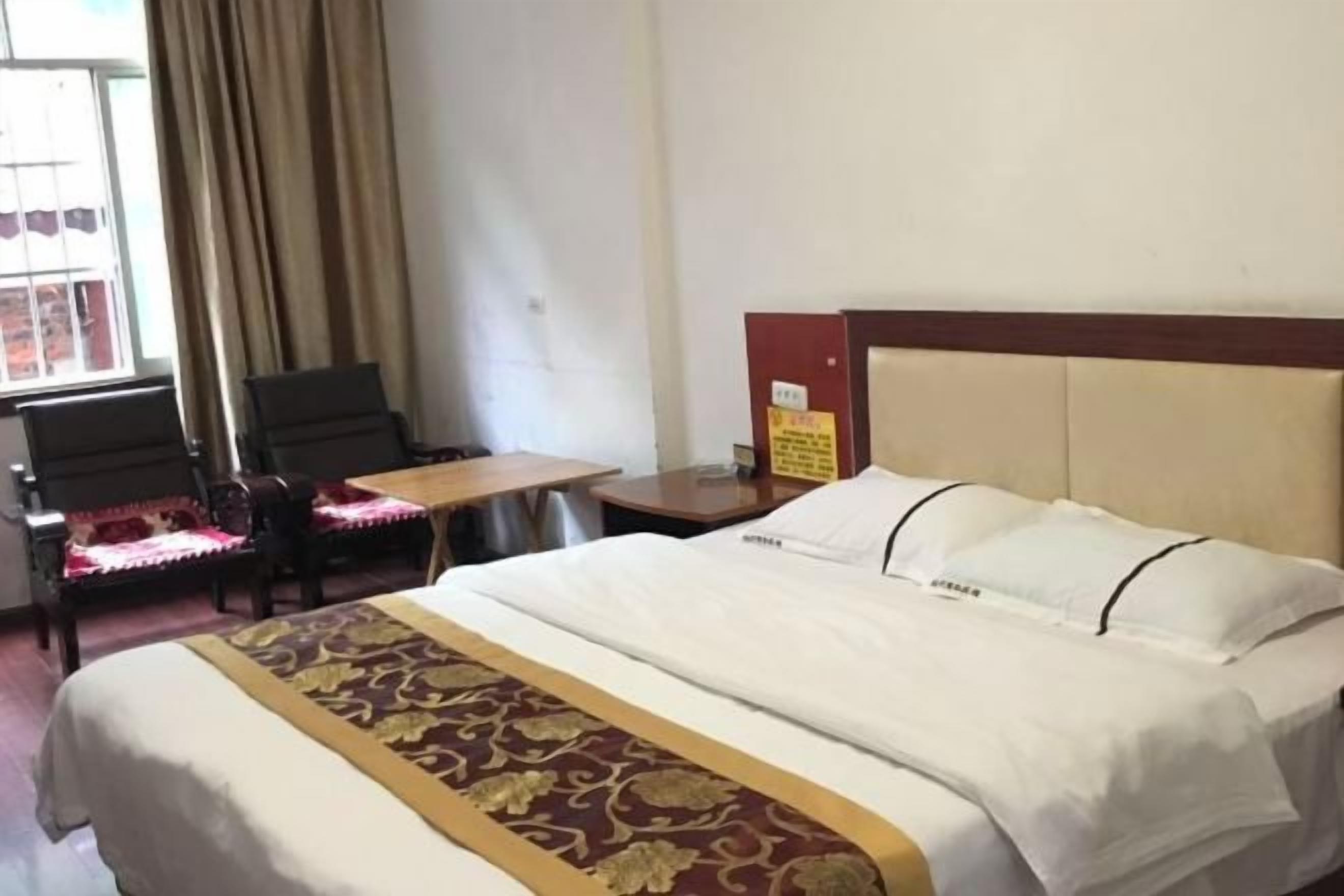 A hotel room with a bed, a desk, a chair, and a window with curtains.