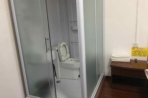 Una cabina de lavabans petita i tancada, amb un vàter blanc i una separació de vidre.