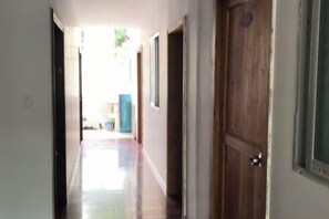 Un pasillo con puertas de madera, un ventanal y una puerta con manija.
