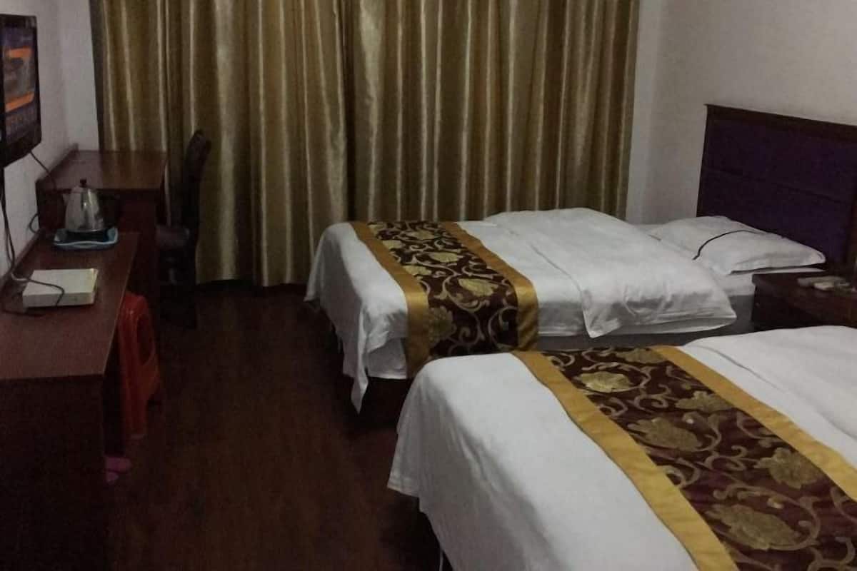 Une chambre d’hôtel avec deux lits, un bureau avec une chaise et un rideau.