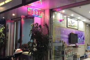 A hotel entrance with a neon sign, a glass door, and a television on the wall. - Modern Business Hotel (Congjiang)