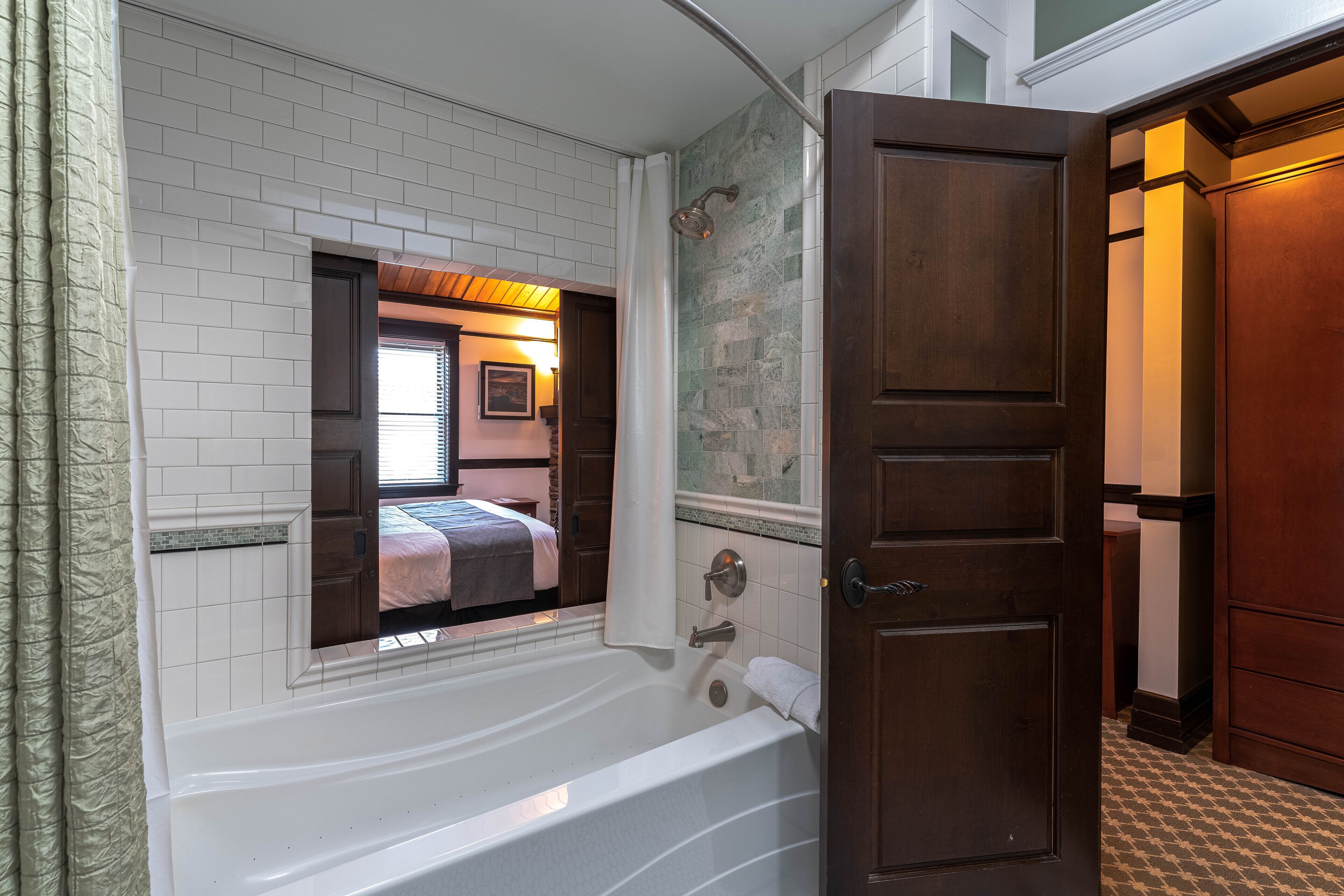 A bathroom with a bathtub, a shower, and a wooden door.