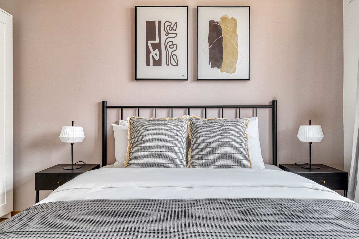 A neatly made bed with a patterned bedspread, two pillows, and two bedside lamps on black nightstands.