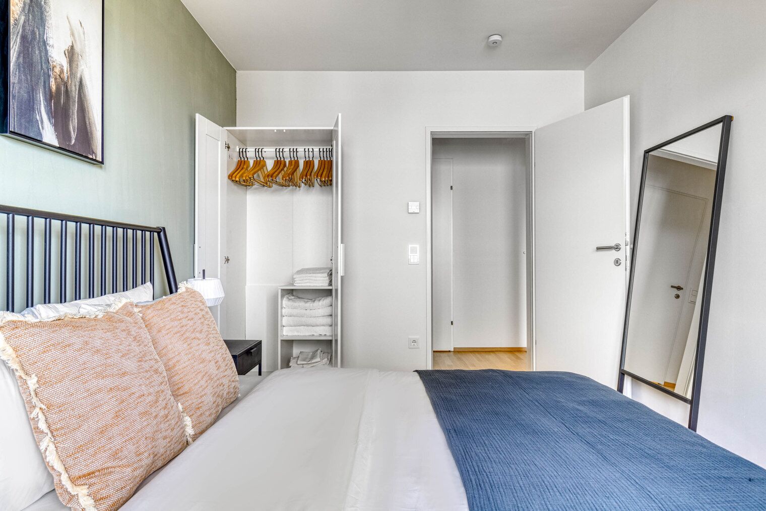 Un dormitorio con cama, armario y espejo.