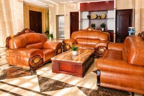 A lobby with leather sofas, a coffee table, and a decorative shelf. - Anyi Hotel (Nantong)