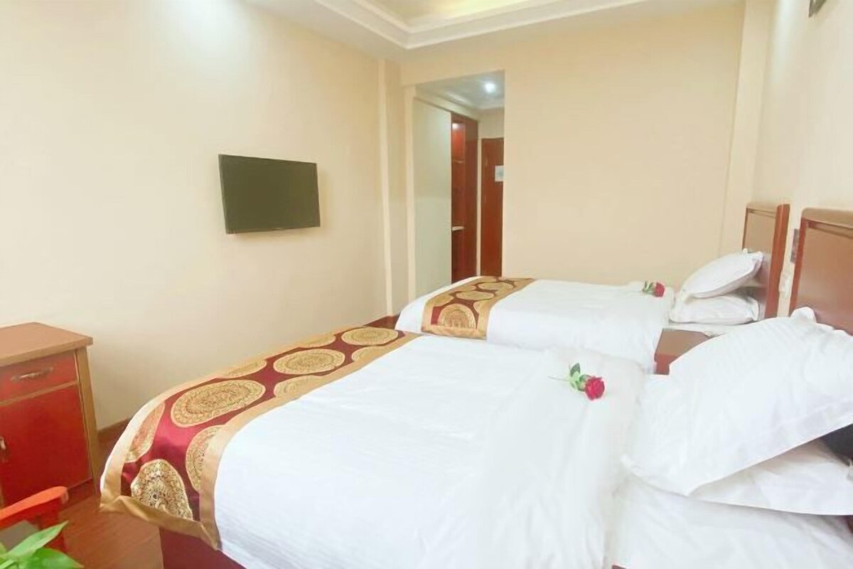 A hotel room with two beds, a TV on the wall, and a red cabinet.