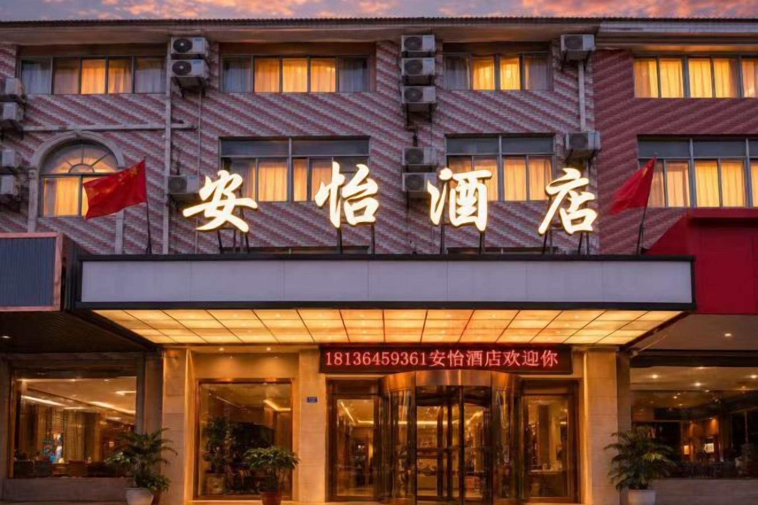 A hotel entrance with a sign that reads '安怡酒店' and a contact number '18136459361'.