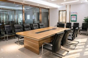 A conference room with a large wooden table, black chairs, and glass walls. - Anyi Hotel (Nantong)