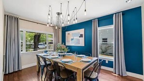 Une salle à manger avec une table en bois dressée pour six personnes, entourée de chaises.
