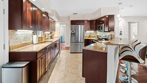 Une cuisine moderne avec des meubles en bois foncé, des appareils électroménagers en acier inoxydable et un îlot central doté de tabourets de bar.
