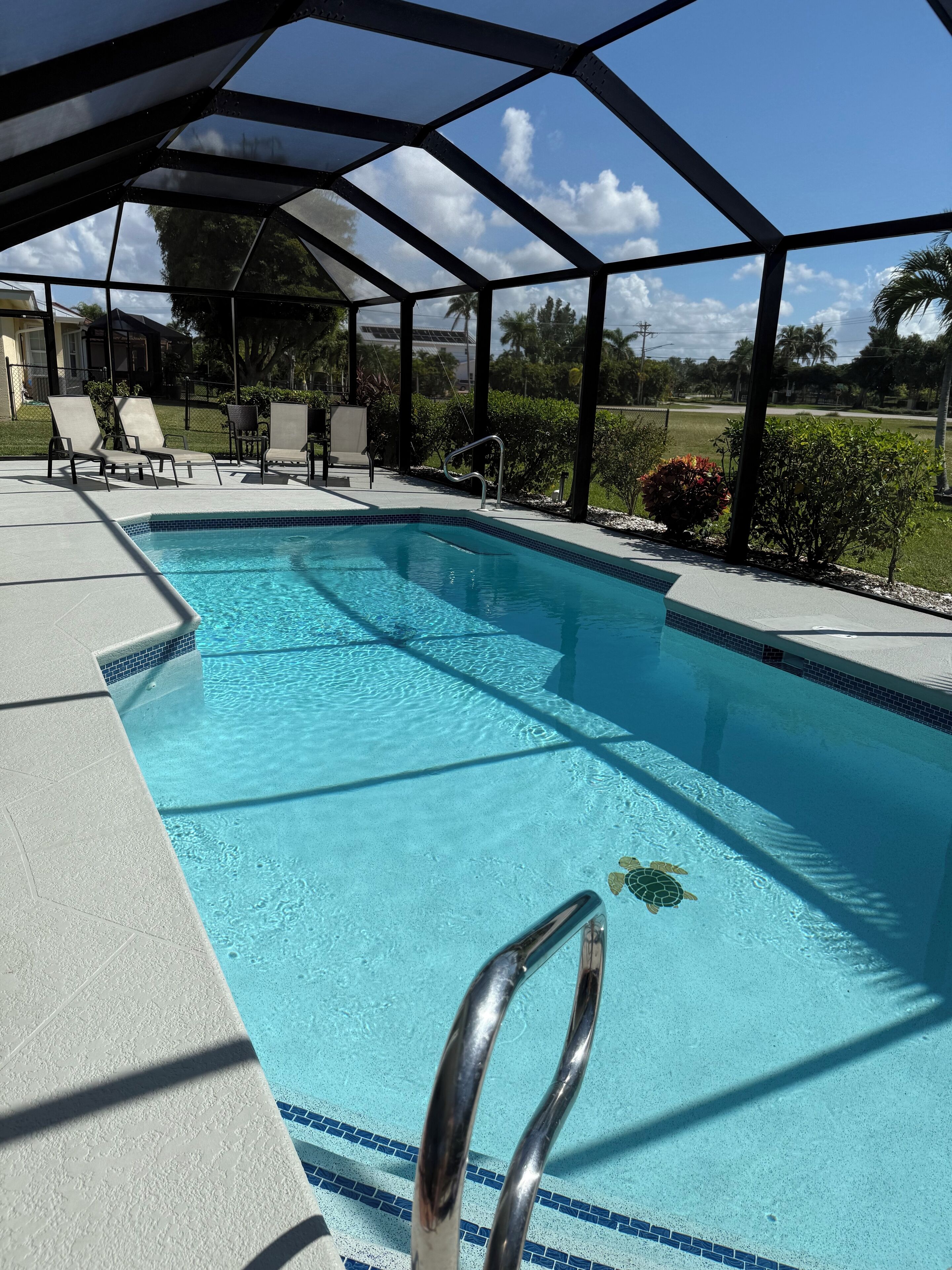 Una piscina con agua cristalina azul, rodeada de sillones de descanso y una zona cubierta.