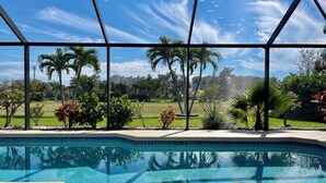 Une piscine offrant une vue dégagée sur les palmiers et s’ouvrant sur une zone verdoyante.