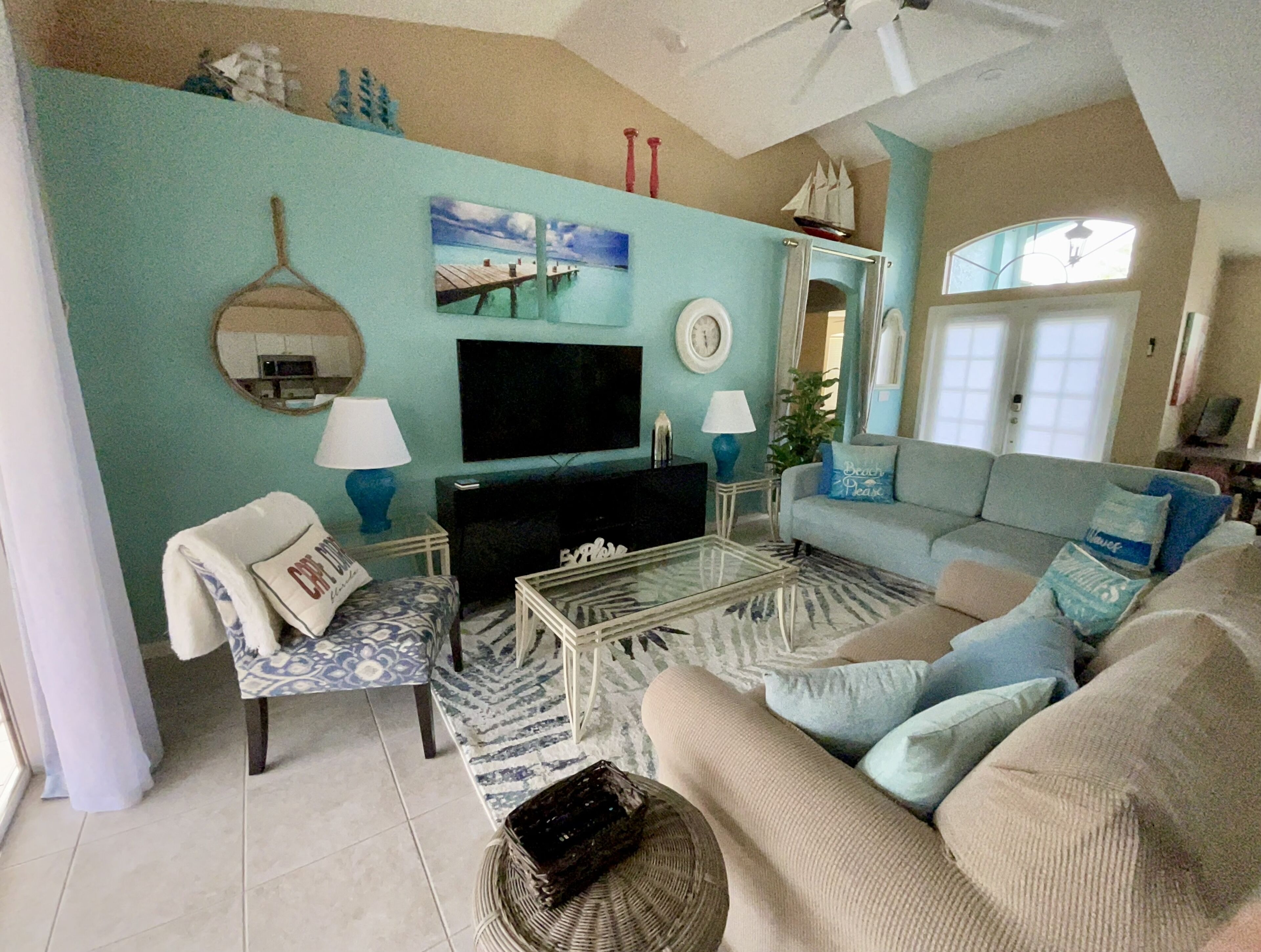 A living room with a sofa, armchair, coffee table, TV, and decorative items.
