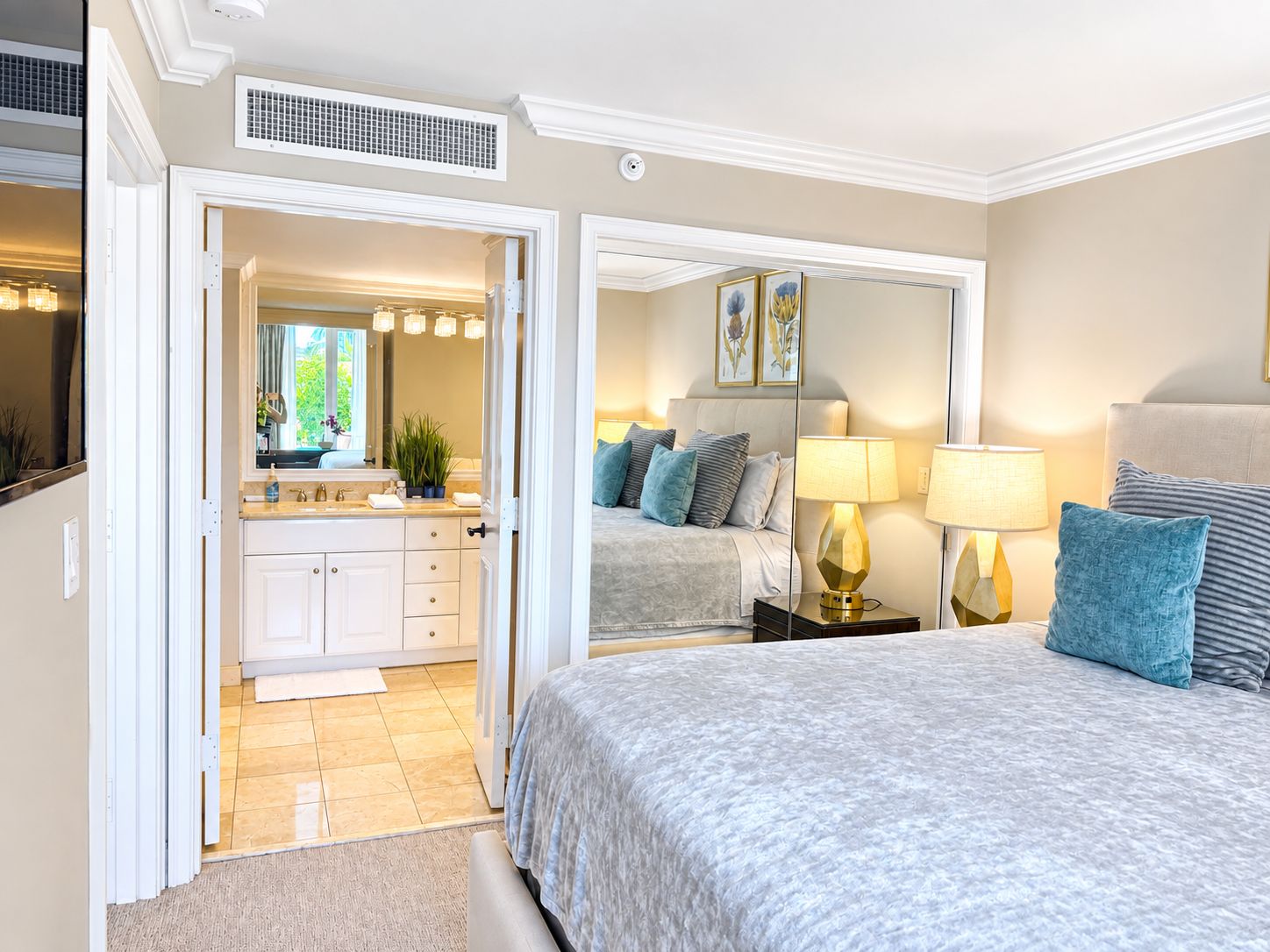 A bedroom with a large bed, bedside lamps, a nightstand, and a mirror.