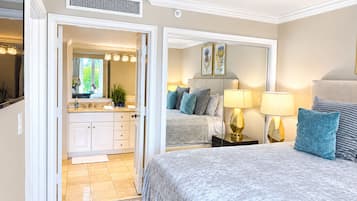 A bedroom with a large bed, bedside lamps, a nightstand, and a mirror.