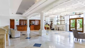 A spacious lobby with a high ceiling, polished marble floors, and a reception area with wooden cabinets.