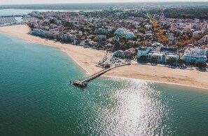 An aerial view of a coastal town with a pier extending into the sea, a sandy beach, and residential buildings. - Apartment in Arcachon (arcachon)