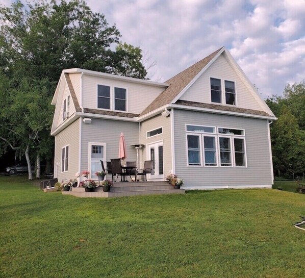 A two-story house with a covered patio and a lawn.