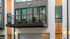A modern two-story building with a balcony, large windows, and a garage.