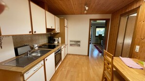 Cocina compacta con armarios de madera, lavavajillas y cafetera.