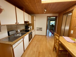 A compact kitchen with wooden cabinets, a dishwasher, and a coffee maker. - Holiday Apartment Fewo 1 am Auweg with Mountain View, Shared Garden & Wi-Fi (Hirschegg)