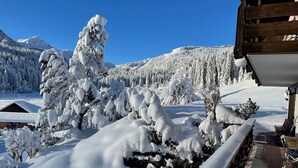 Paisaje nevado con una construcción de madera y cielo azul despejado.