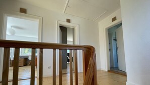 A spacious room with wooden flooring, white walls, and a wooden railing. There are multiple doorways leading to other rooms. - Holiday Home "Hofberg Villa" with Terrace, Open Garden and High-speed Wi-Fi (Landshut)