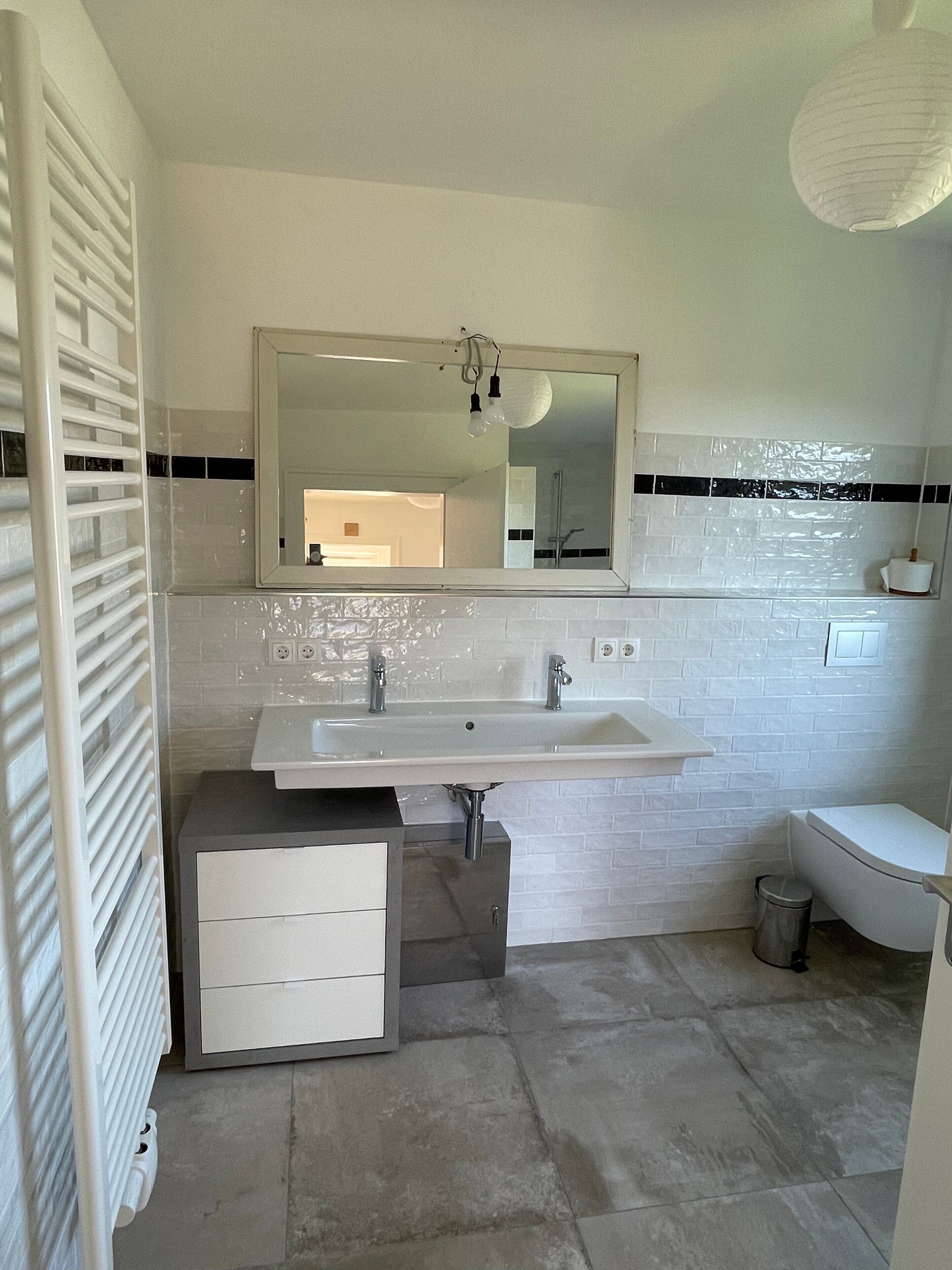 Un baño con lavamanos, espejo y retrete blancos.