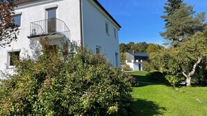 A white building with a balcony, surrounded by greenery and trees. - Holiday Home "Hofberg Villa" with Terrace, Open Garden and High-speed Wi-Fi (Landshut)