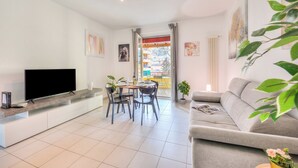 A modern living room with a flat-screen TV, dining table, chairs, a sofa, and a potted plant. - Casa Rosa with Balcony in Lugano, Lugano, Switzerland (Lugano)