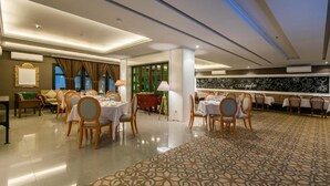 Une salle à manger d’hôtel avec des tables dressées pour les clients, une moquette à motifs et un mur orné d’un décor de style graffiti.