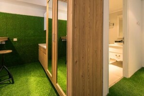 Een kamer met een houten garderobe, een spiegel en een vloer van groen kunstgras.
