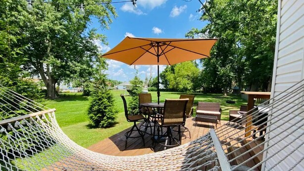 Une terrasse avec un hamac, une table et des chaises, et un parasol.