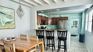 Une cuisine moderne avec des meubles en bois, un réfrigérateur en acier inoxydable et un coin repas comprenant une table et des chaises en bois.