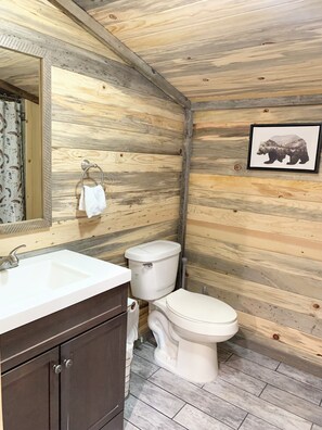 A bathroom with wooden walls, a white sink, and a toilet. - Blue Pine Guesthouse MT (Dillon)