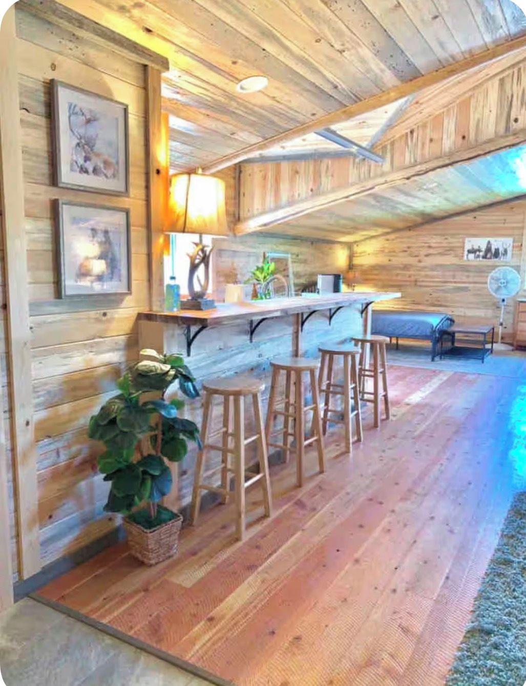 Ein rustikales Holzinterieur mit Barbereich, Holzboden und gerahmten Kunstwerken an den Wänden.