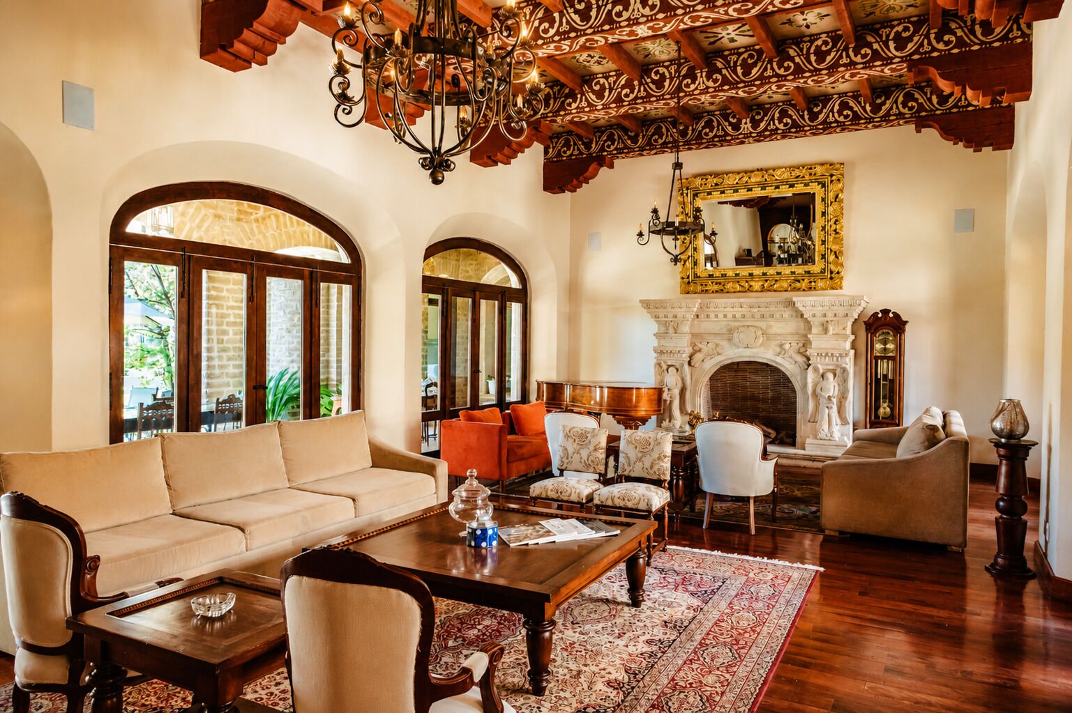 A spacious living room with a fireplace, arched windows, and ornate ceiling details.