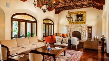 A spacious living room with a fireplace, arched windows, and ornate ceiling details.