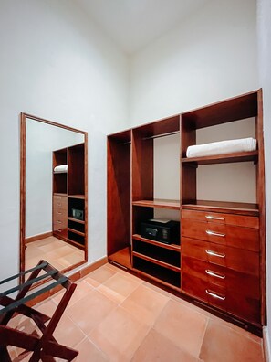 Un vestidor con estantes y cajones de madera, un espejo y una silla.