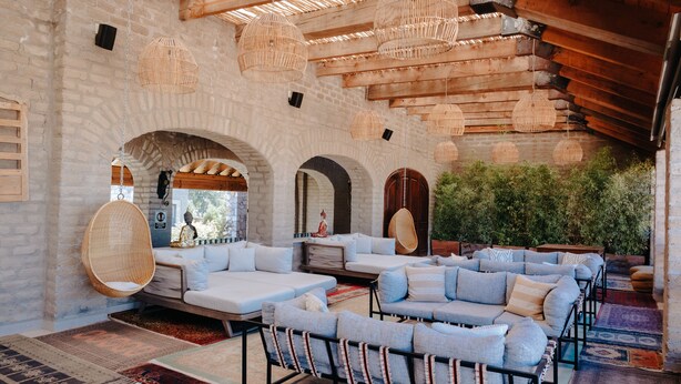 A spacious lounge area with a modern sofa set, hanging wicker lamps, and a view of greenery outside. - Hacienda los Arcangeles (San Miguel de Allende)