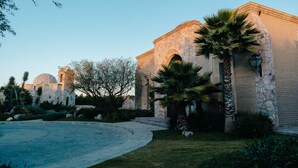 A historic building with stone architecture, palm trees, and a clear sky. - Hacienda los Arcangeles (San Miguel de Allende)
