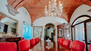 A large, polished wooden conference table with red upholstered chairs, a chandelier, and a large mirror on one side. - Hacienda los Arcangeles (San Miguel de Allende)