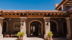 A building with a tiled roof, stone arches, and potted plants in the entrance area. - Hacienda los Arcangeles (San Miguel de Allende)