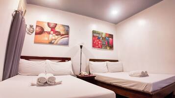 A hotel room with two beds, white linens, a telephone, and two paintings on the wall.