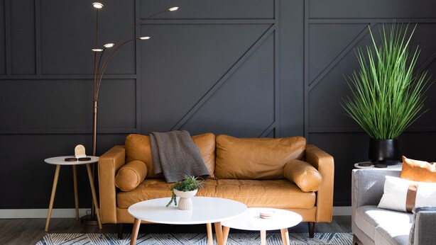 A modern living room with a brown leather sofa, two white round tables, a tall floor lamp, and a large green plant. - Luxury MCM King Suite • Coffee Lover's Dream! • EV2 (Salem)