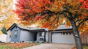 A residential house with a garage, a driveway, and a tree with autumn leaves. - Luxury MCM King Suite • Coffee Lover's Dream! • EV2 (Salem)