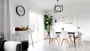 A modern dining area with a white table, black chairs, and a large plant. - Luxury MCM King Suite • Coffee Lover's Dream! • EV2 (Salem)