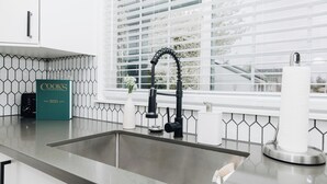 A kitchen with a modern faucet, a cookbook, and a window with blinds. - Luxury MCM King Suite • Coffee Lover's Dream! • EV2 (Salem)
